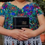 woman in blue white and pink floral crew neck t-shirt holding black box