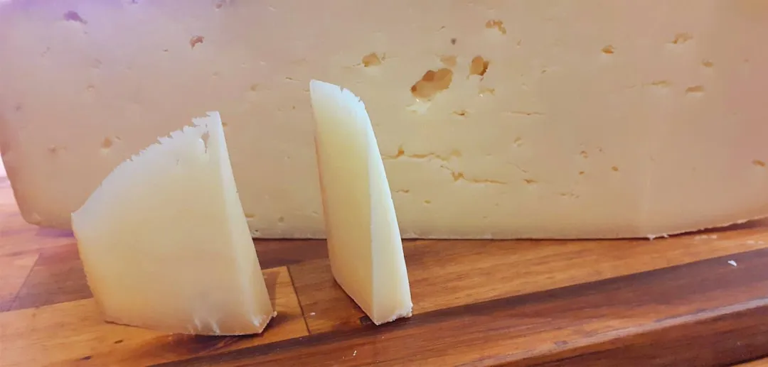 Cheese wedges with a block of cheese in the background.