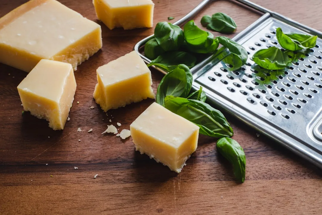 sliced cheese beside green leaves on brown wooden table