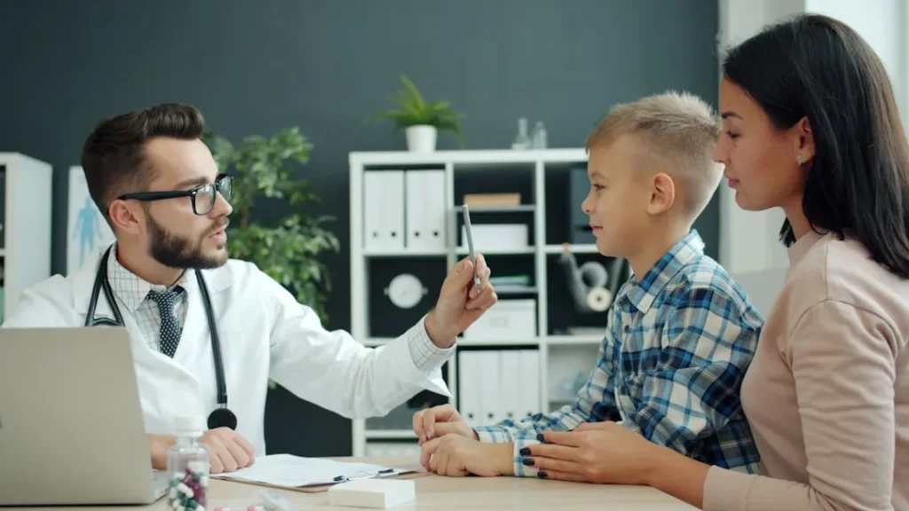 Doctor examines a young boy with his mother present.