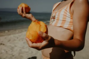Person holding peaches on a sunny beach