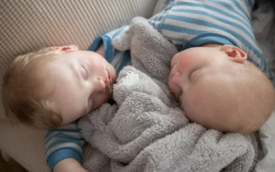 a couple of babies laying next to each other on a couch