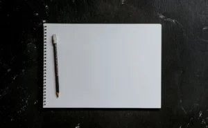 Blank notebook with a pen on a dark surface