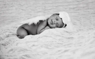 grayscale photo of baby lying on white textile