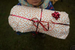 a child holding a wrapped present wrapped in polka dot paper