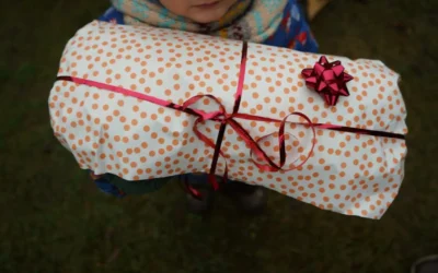 a child holding a wrapped present wrapped in polka dot paper