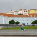 A woman walking down a street in front of a blue building