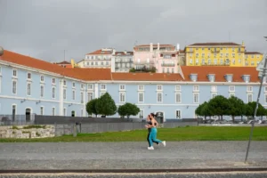 A woman walking down a street in front of a blue building