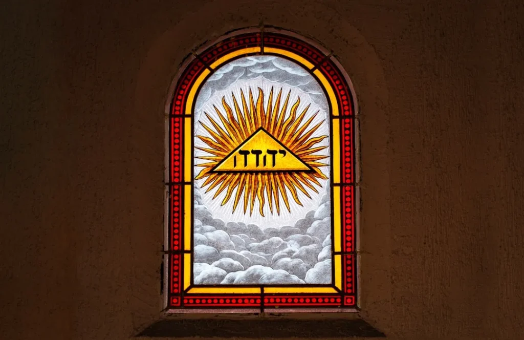 a stained glass window with a triangle and sun