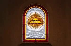 a stained glass window with a triangle and sun