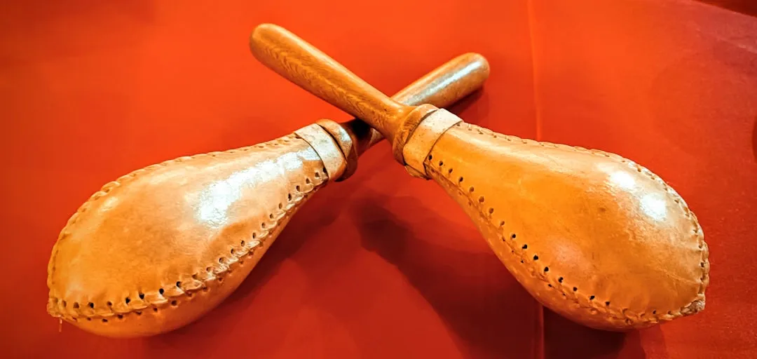 Two maracas are pictured on a red surface.