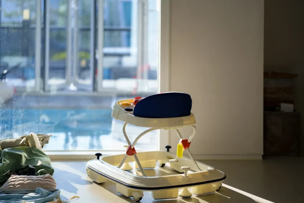 A baby walker sits by a sunlit window.