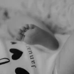 babys foot on white and black textile