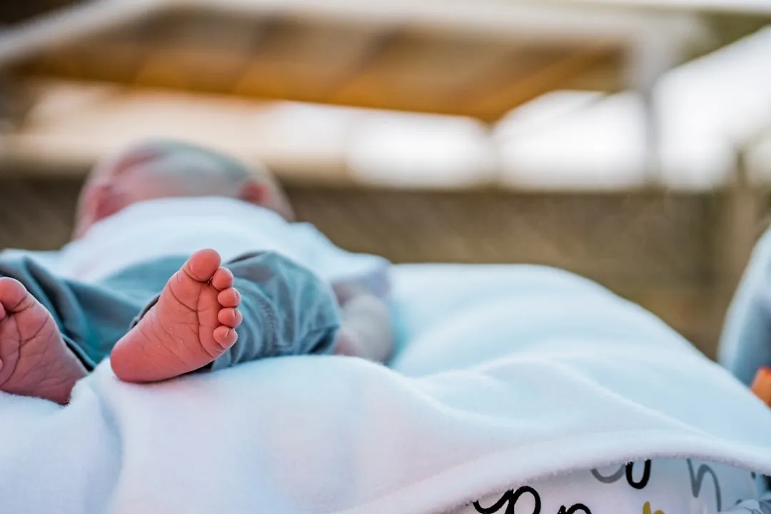 baby in blue onesie lying on bed