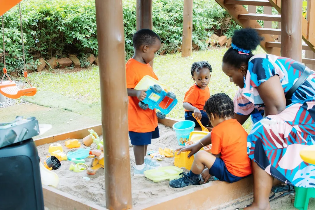 Children playing in a sandbox with an adult