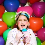 A young girl is sitting in front of a bunch of balloons