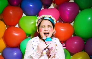 A young girl is sitting in front of a bunch of balloons