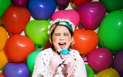 A young girl is sitting in front of a bunch of balloons