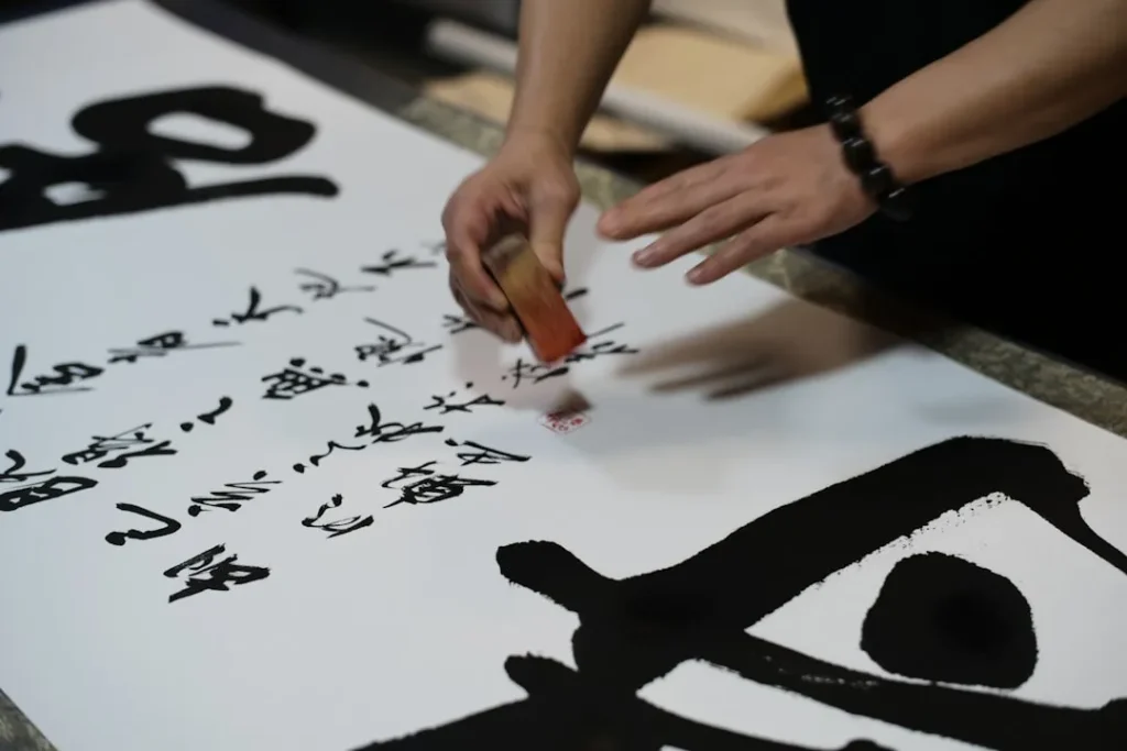 Artist writing calligraphy on large white paper