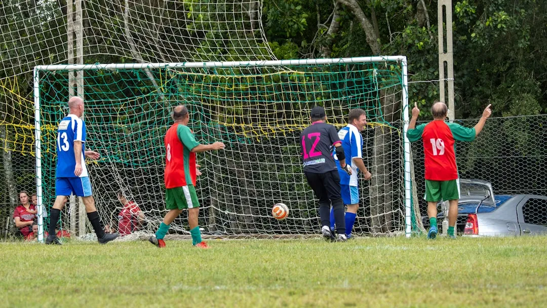 Men playing soccer near a goal on a grassy field