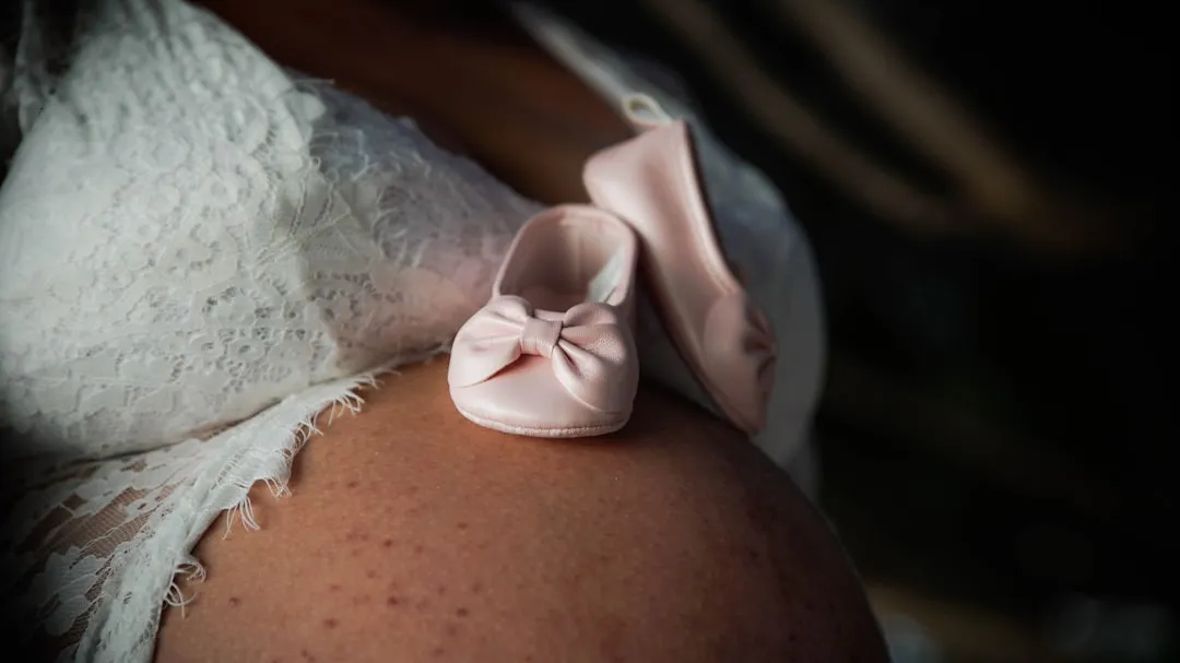 a close up of a pregnant woman's belly with a pink bow