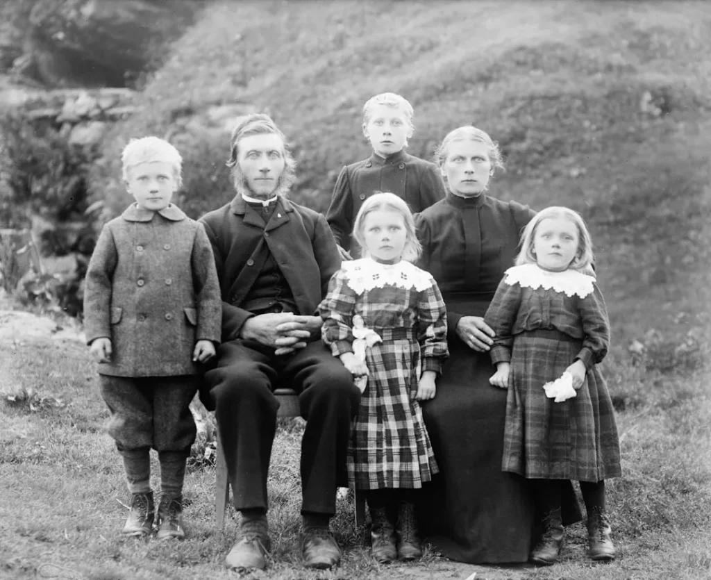 A victorian family poses for a formal outdoor portrait.