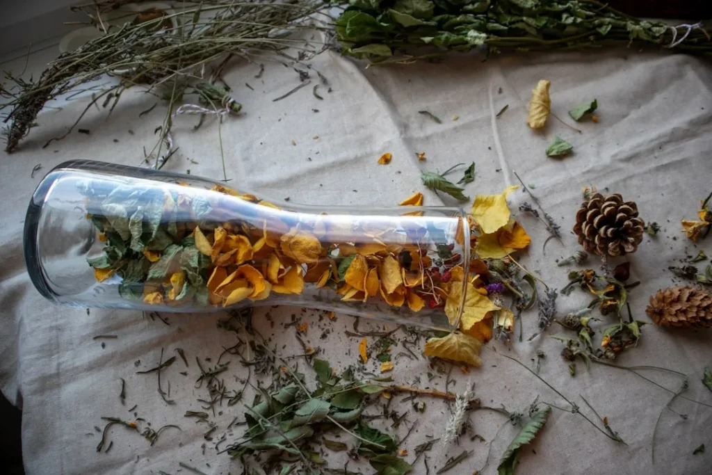 A bottle filled with flowers and leaves on top of a table
