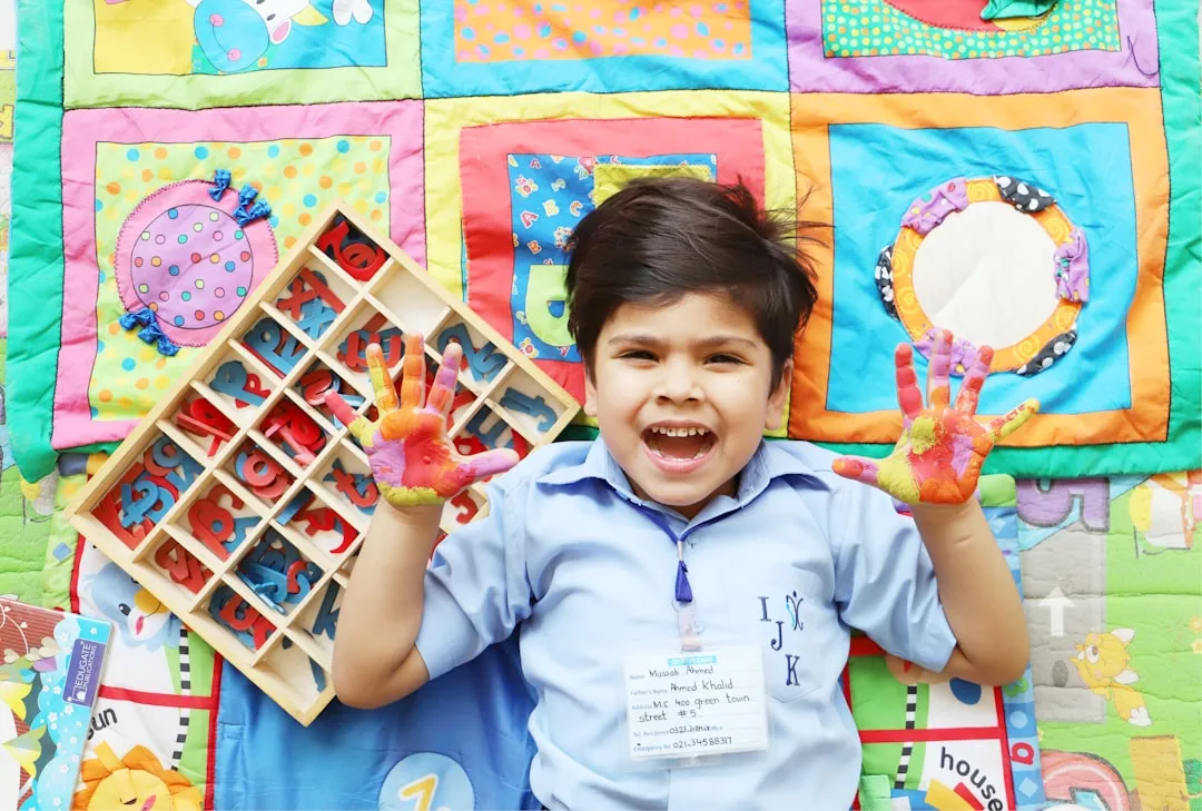 Young boy with colorful painted hands and alphabet blocks.