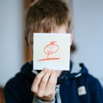 boy holds white card with drawing