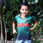 a young boy standing in front of a tree