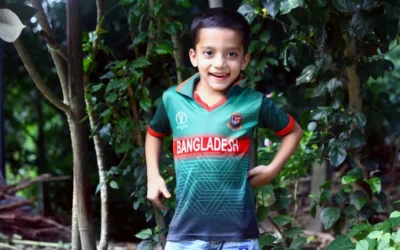 a young boy standing in front of a tree