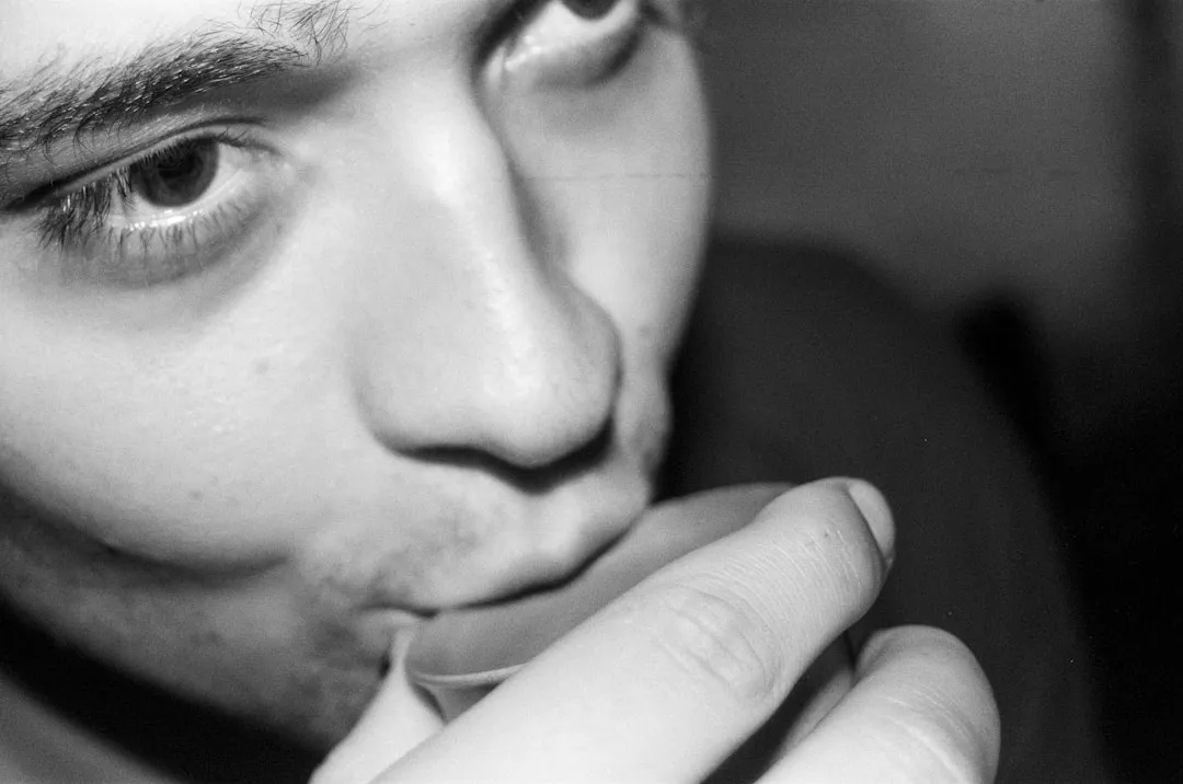 Close-up of a person drinking from a small glass.