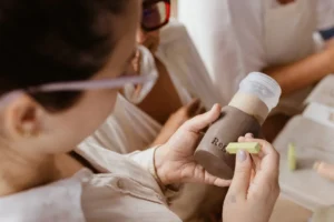 A woman is holding a bottle and looking at it