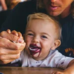 a woman feeding a child a spoon of food
