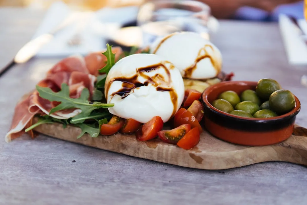 Burrata, tomatoes, and olives on a wooden platter.