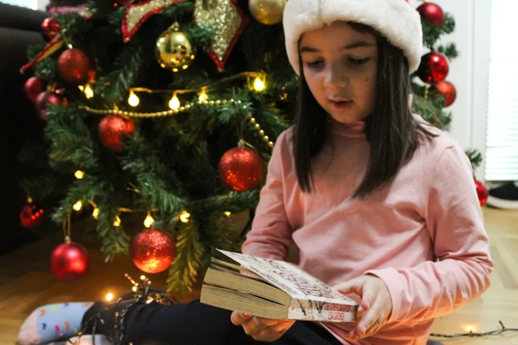 a little girl sitting on the floor reading a book