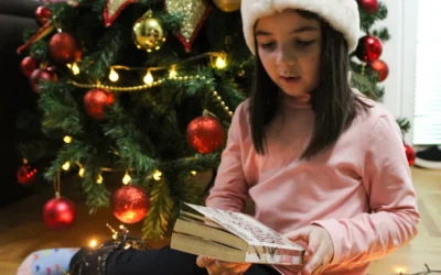 a little girl sitting on the floor reading a book