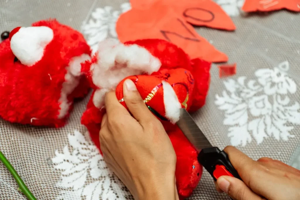Hands stuffing red heart ornaments with white filling
