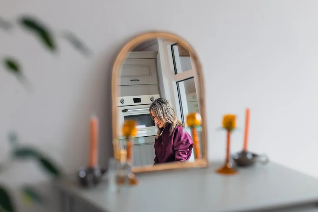Woman reflected in a wooden arched mirror.