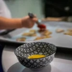 a bowl of food on a table with a person in the background