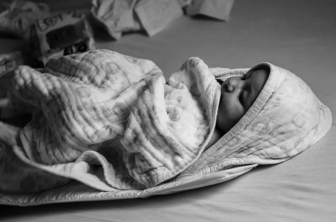 grayscale photo of baby covered with blanket