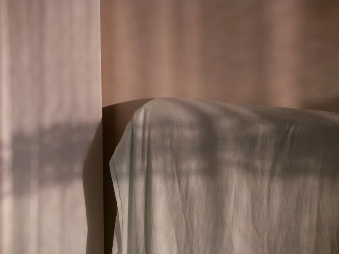 Sunlight casts shadows on a draped surface.