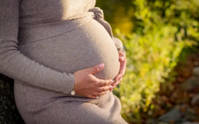 pregnant woman wearing gray long-sleeved dress touching her tummy while standing
