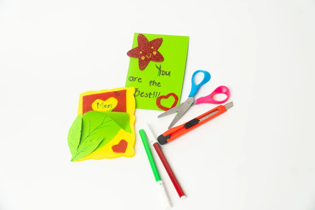 Craft supplies and handmade cards on white background.