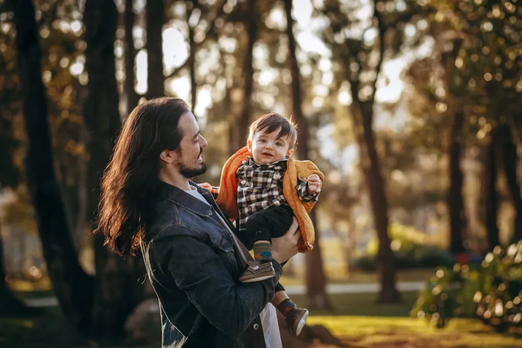 woman in blue denim jacket carrying baby in black and white striped long sleeve shirt during