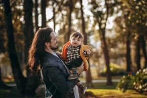woman in blue denim jacket carrying baby in black and white striped long sleeve shirt during
