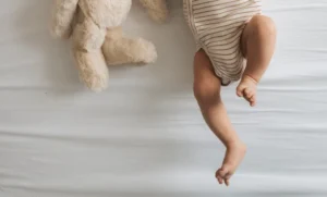 a baby laying on a bed next to a teddy bear