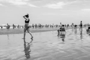 People walking on a wet sandy beach near the ocean.
