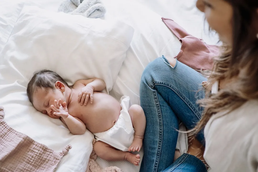 a baby laying on a bed next to a woman