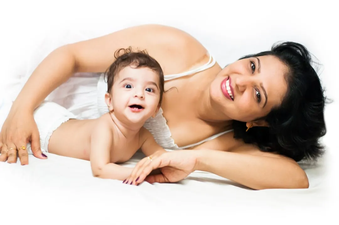 Happy mother and baby smiling on a clean white surface.